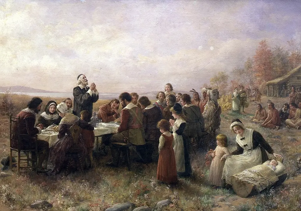 17th-century group of pilgrims and native americans gathered outdoors for a communal meal, featuring a prayerful moment.