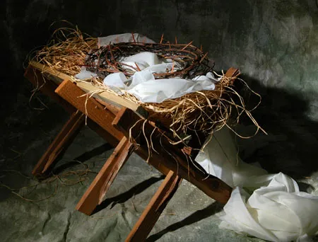 Artistic representation of a bird's nest with eggs on a wooden stool surrounded by tattered fabric.