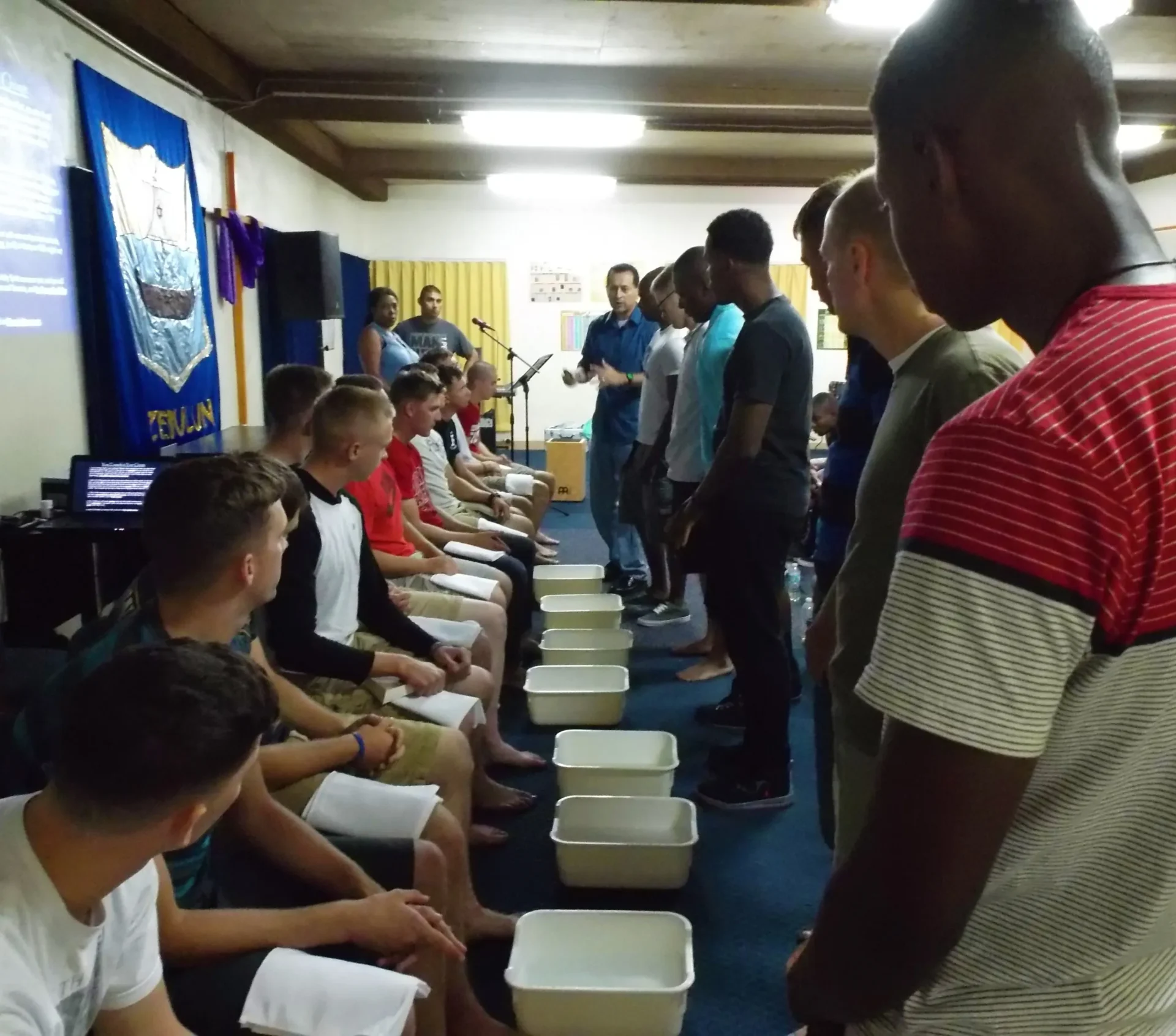 Men participating in a foot-washing ceremony indoors.