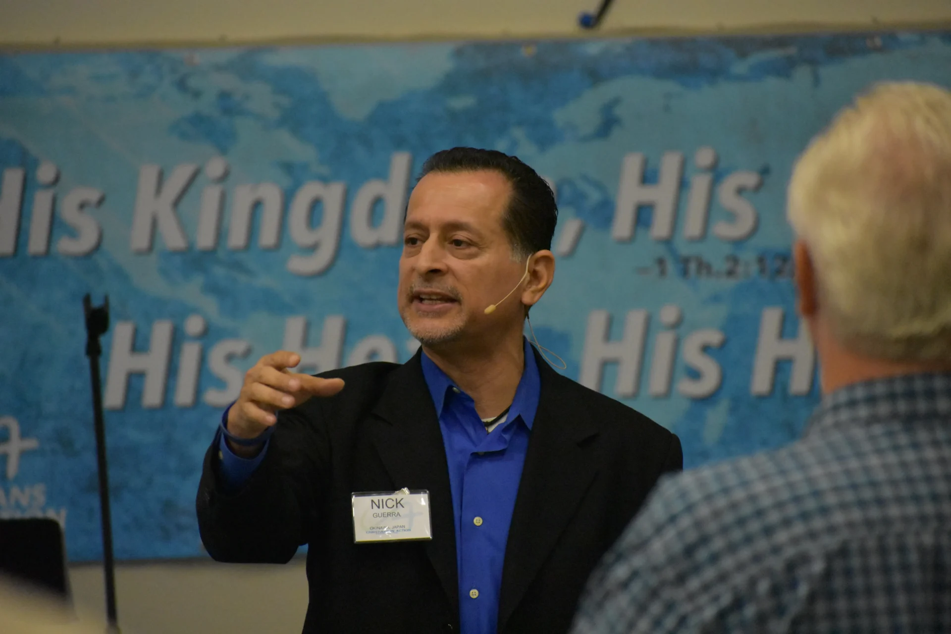 Man giving a presentation with a world map in the background.