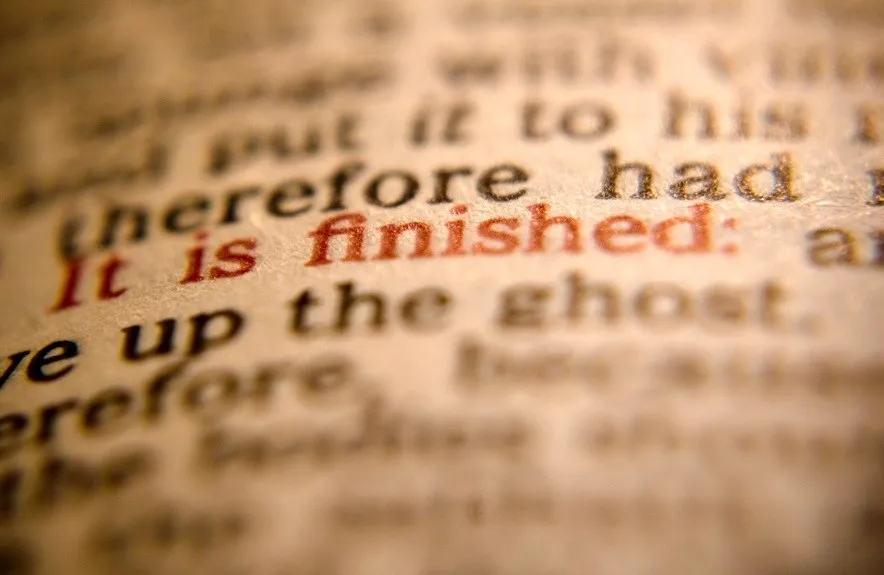 A close-up of printed text with the phrase "it is finished" in red, highlighted by a shallow depth of field.