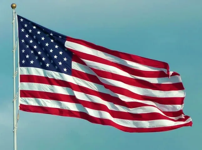 The american flag waving against a blue sky.