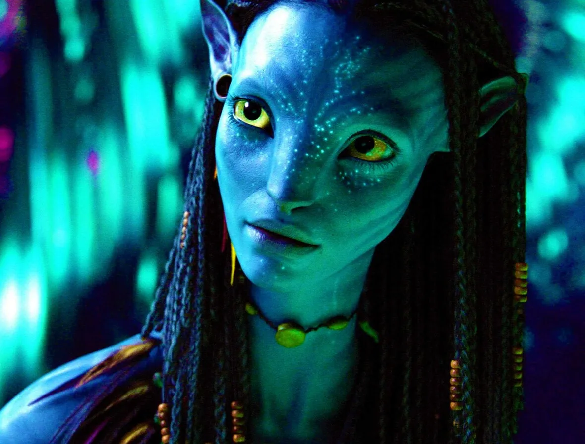 A close-up image of a blue-skinned, wide-eyed, alien character with intricate facial markings and braided hair from a science fiction setting.