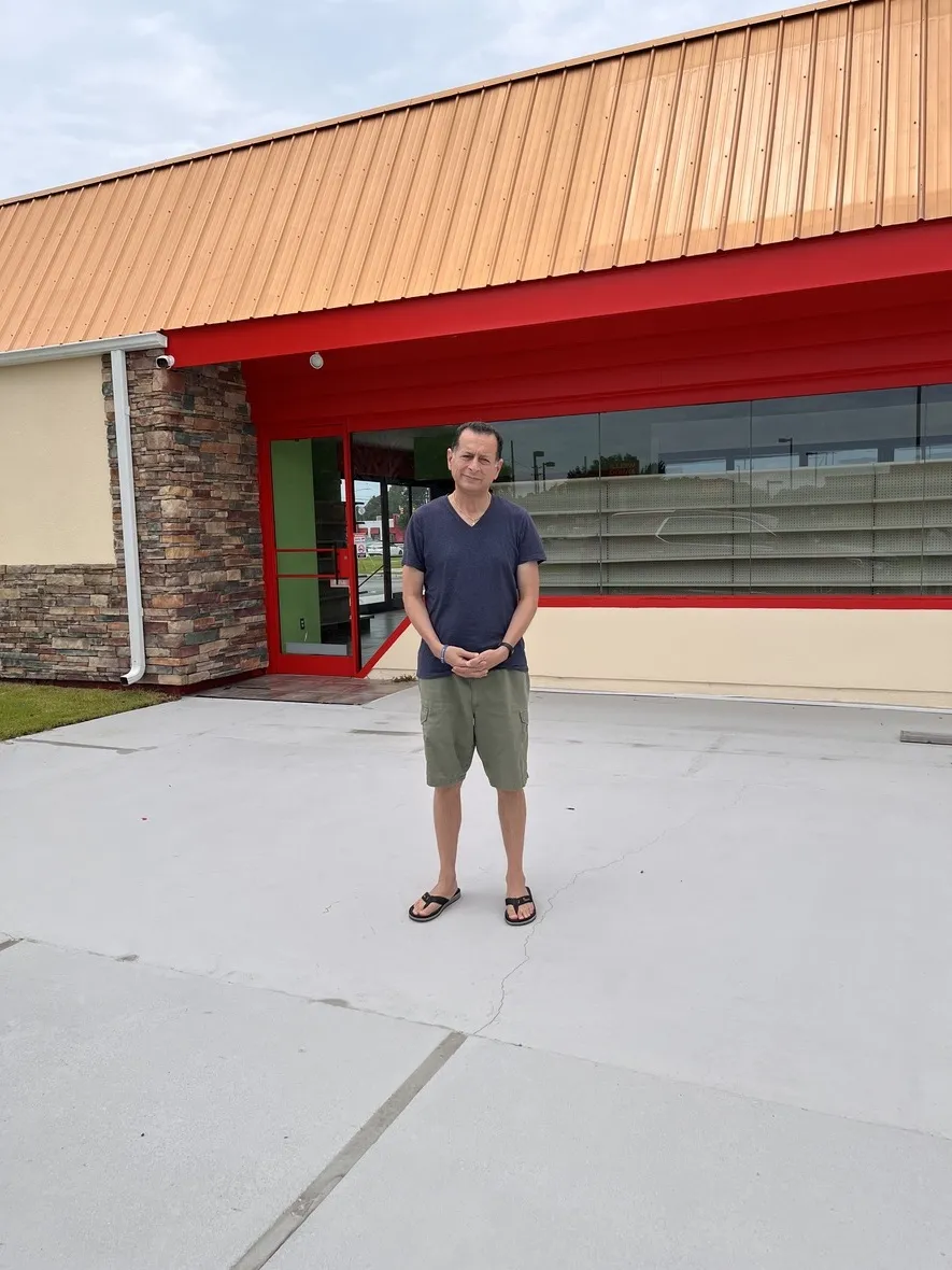 Man standing in front of a building with a red awning.