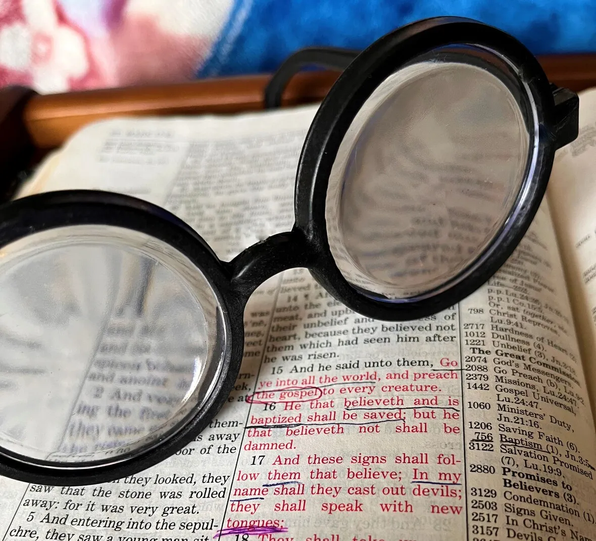 Round glasses resting on an open bible with text in focus through the lenses.