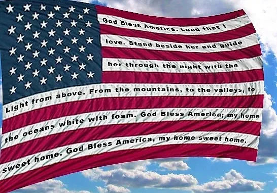 An american flag with the lyrics of "god bless america" superimposed over it, set against a sky with clouds.