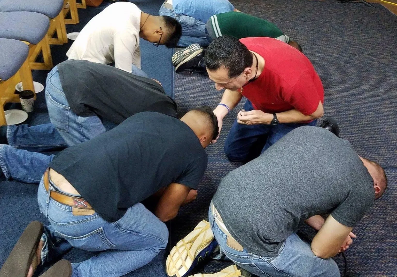 Group of men bowing their heads in prayer.