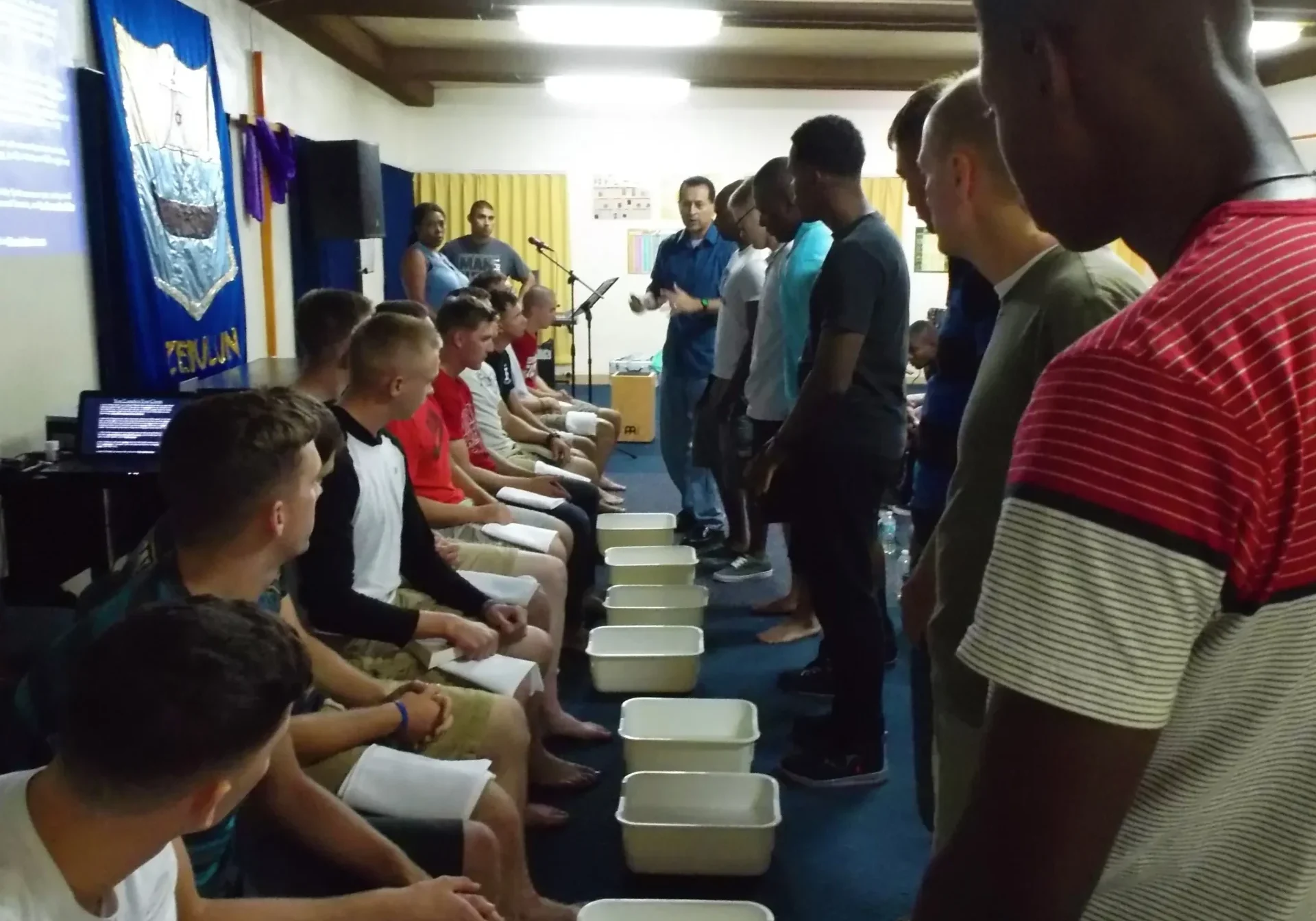 Men participating in a foot-washing ceremony indoors.