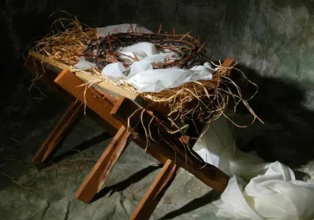 Artistic representation of a bird's nest with eggs on a wooden stool surrounded by tattered fabric.