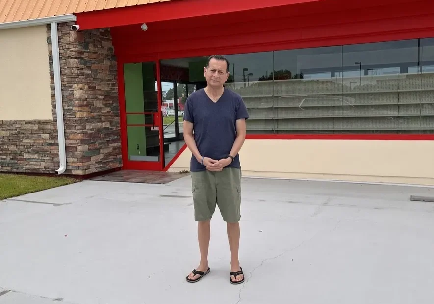 Man standing in front of a building with a red awning.