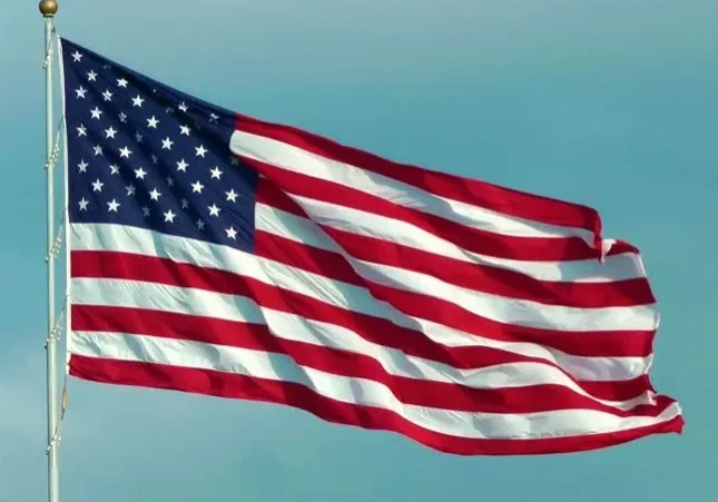 The american flag waving against a blue sky.