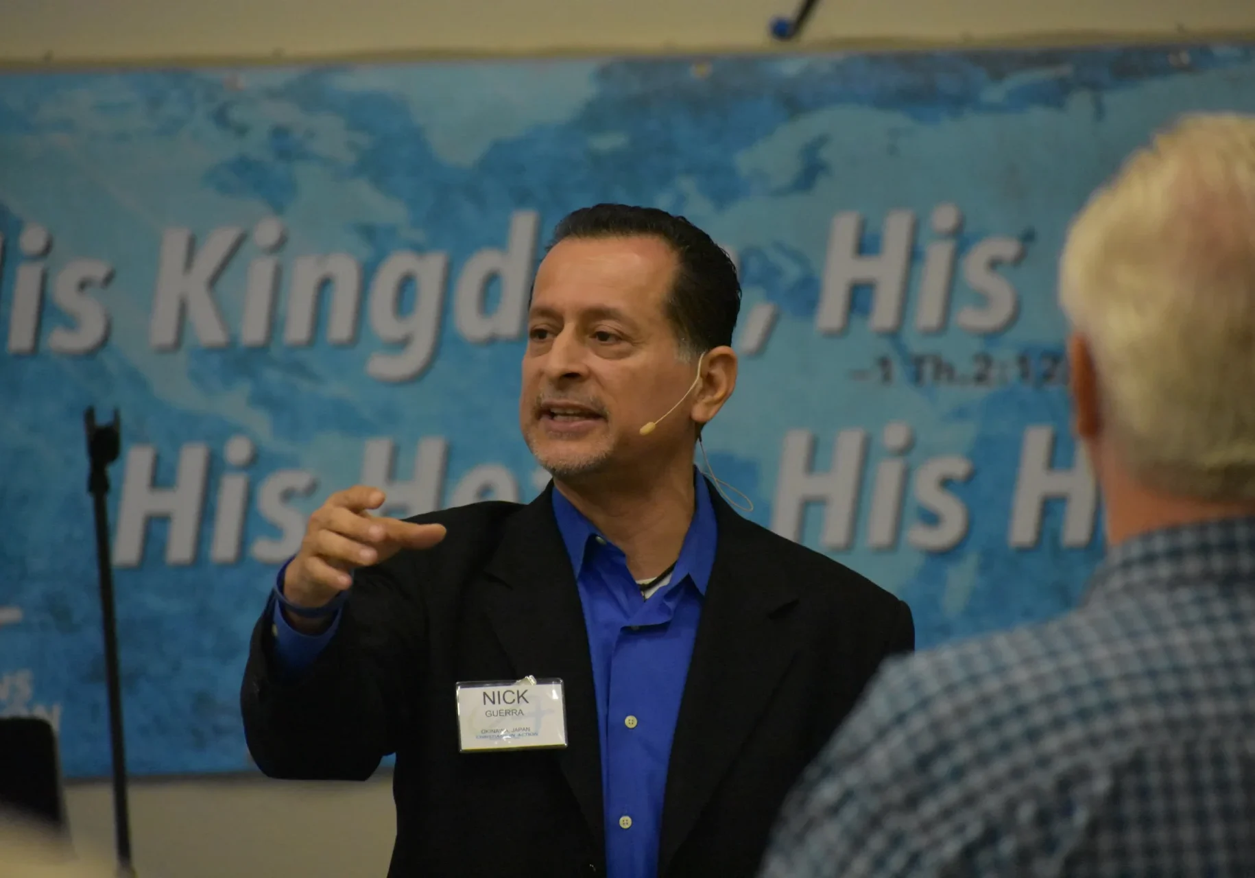 Man giving a presentation with a world map in the background.