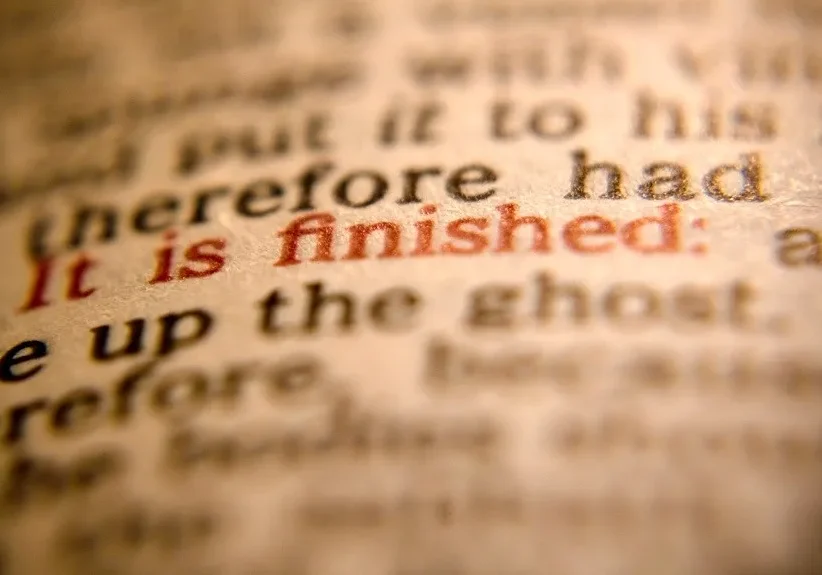 A close-up of printed text with the phrase "it is finished" in red, highlighted by a shallow depth of field.